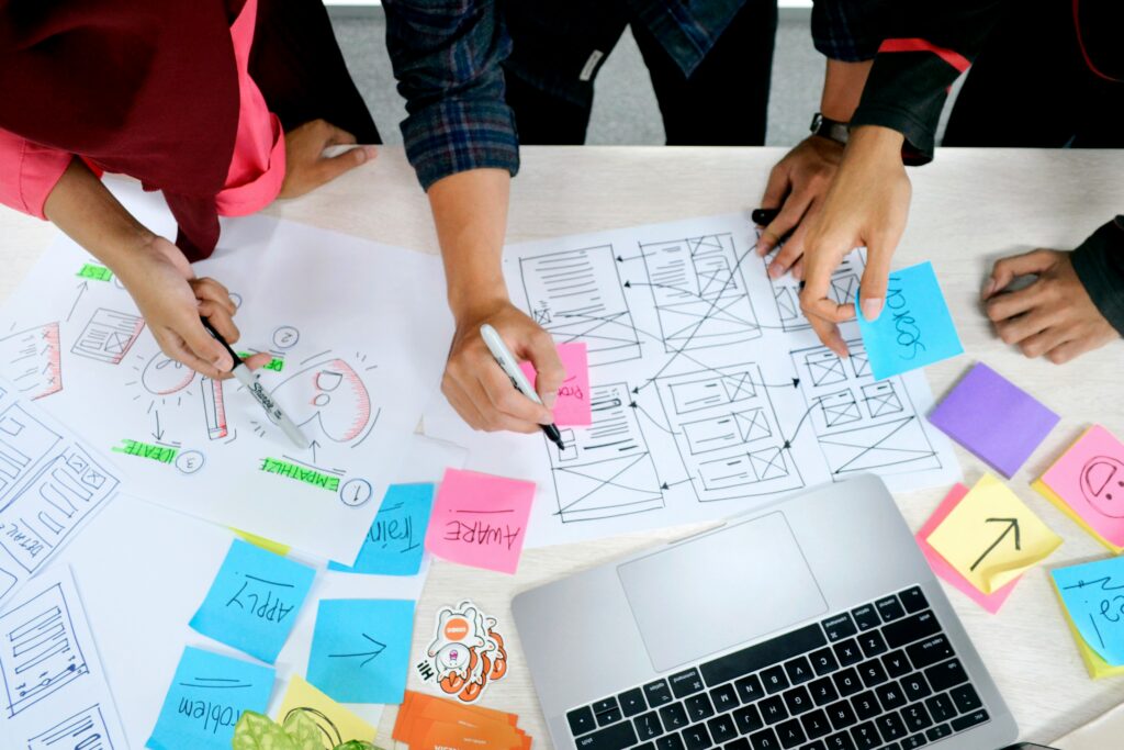 People working at a messy desk with designs and notes spread around